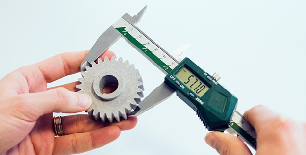 Someone measuring a cog wheel from a 3d printer