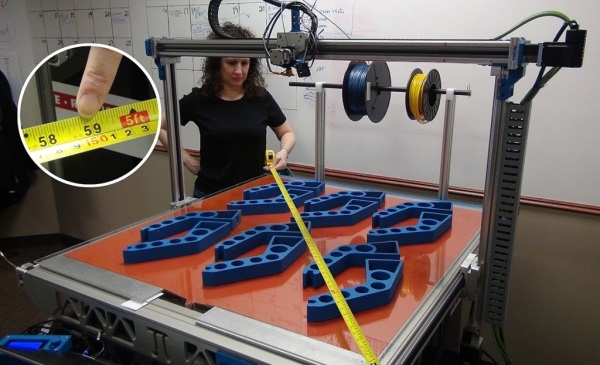 A woman measuring across a large 3D printer, with a glass bed, (diagonally) to measure 59" l create designs for 3D printing